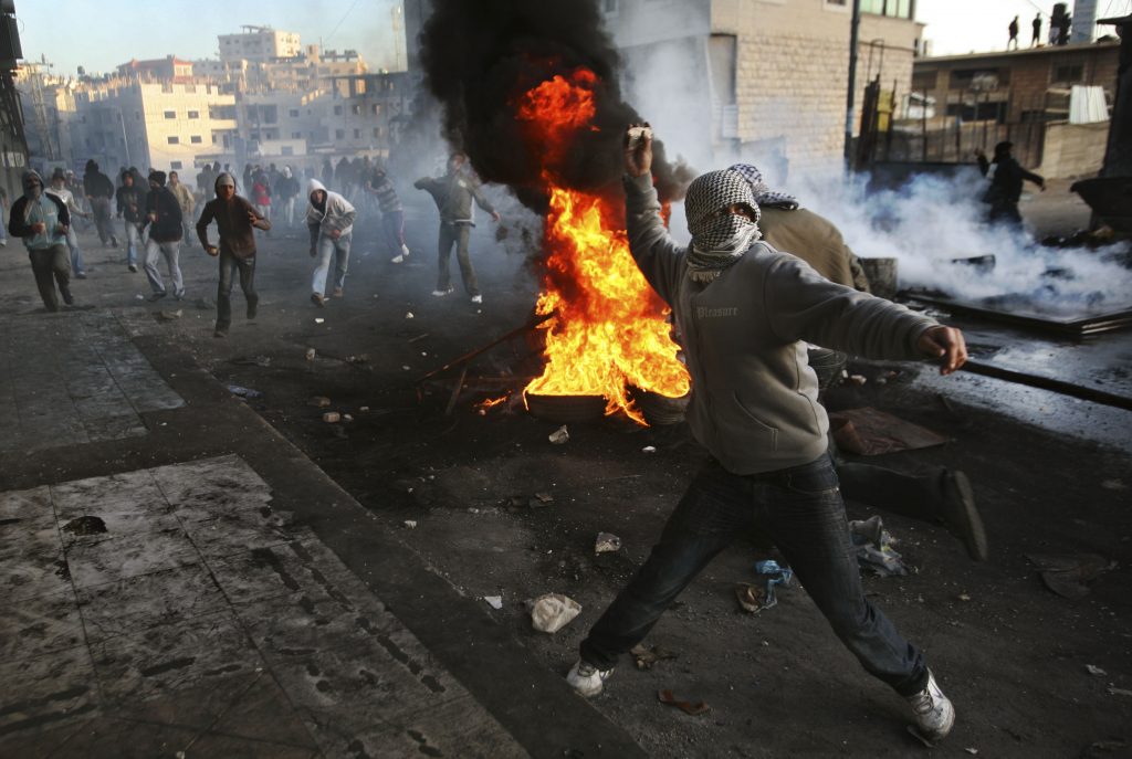A Palestinian protester throws stones at Israeli troops, not seen, during clashes at a demonstration against Israel's military operation in Gaza, in the Shuafat refugee camp, on the outskirts of Jerusalem, Sunday, Dec. 28, 2008. More than 280 Palestinians have been killed and more than 600 people wounded since Israel's campaign to quash rocket barrages from Gaza began midday Saturday. (AP Photo/Dan Balilty)