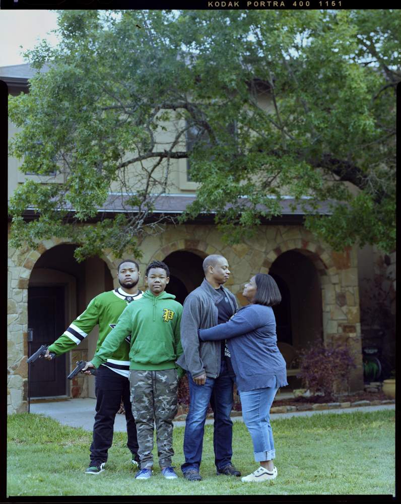 Brothers Dorian Black, 20, from left, and Ashton Black, 13, postures their firearm as Datrelle  Black, 46, is embraced by his wife Rohonda Black, 44, outside of their home on Sunday, April 18, 2021 in Killeen, Tx. “For my children I take the curiosity out of it, total avoidance of guns teaches fear we should inform our children of gun safety,” Datrelle said.