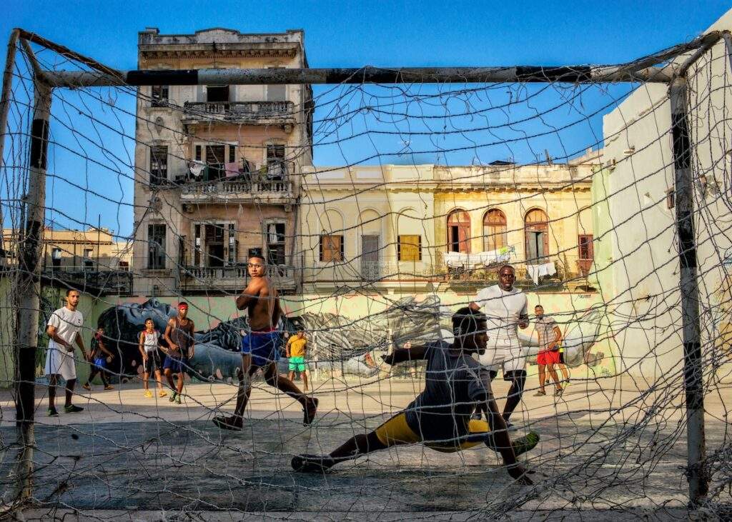 Young men play a heated game of soccer in a movie set-like urban soccer field in the middle of Old Havana, Cuba on May 6, 2016. Soccer or football as it is called outside the US has become a more popular than baseball as a street sport lately in Cuba. (©2016 Dotan Saguy)